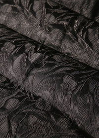 Close-up detail of black embossed floral jacquard fabric on women's goose down jacket