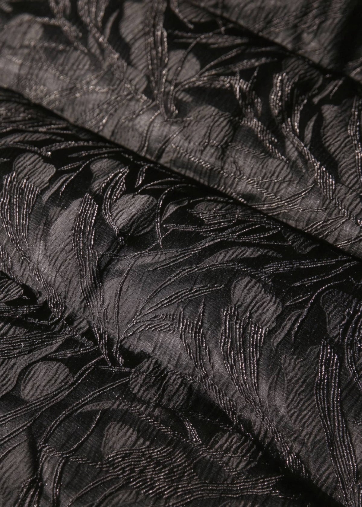 Close-up detail of black embossed floral jacquard fabric on women's goose down jacket
