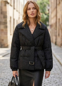 Front view of woman wearing black textured jacquard goose down coat with lapel collar and belted waist