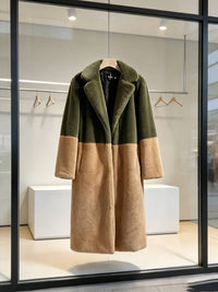 Olive green and camel two-tone faux fur long coat on display in a modern store window.