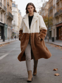 Model walking forward with coat fluttering in an off-white and camel earthy colorblock faux fur long coat.