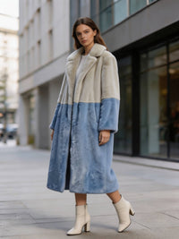 Three-quarter shot of a woman wearing a cream and slate blue plush two-tone faux fur long coat styled with white boots.