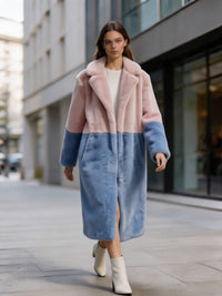 Model walking down a city street in a dusty pink and slate blue two-tone long faux fur coat with heels.