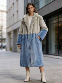 Woman posing outdoors in a cream and slate blue two-tone notch collar faux fur long coat with hand in pocket.
