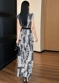 A rear view of the woman walking away, highlighting the high-waisted fit and the floor-length wide-leg silhouette of the printed jumpsuit. She is carrying a black crocodile-pattern handbag, and her long black hair falls down her back.