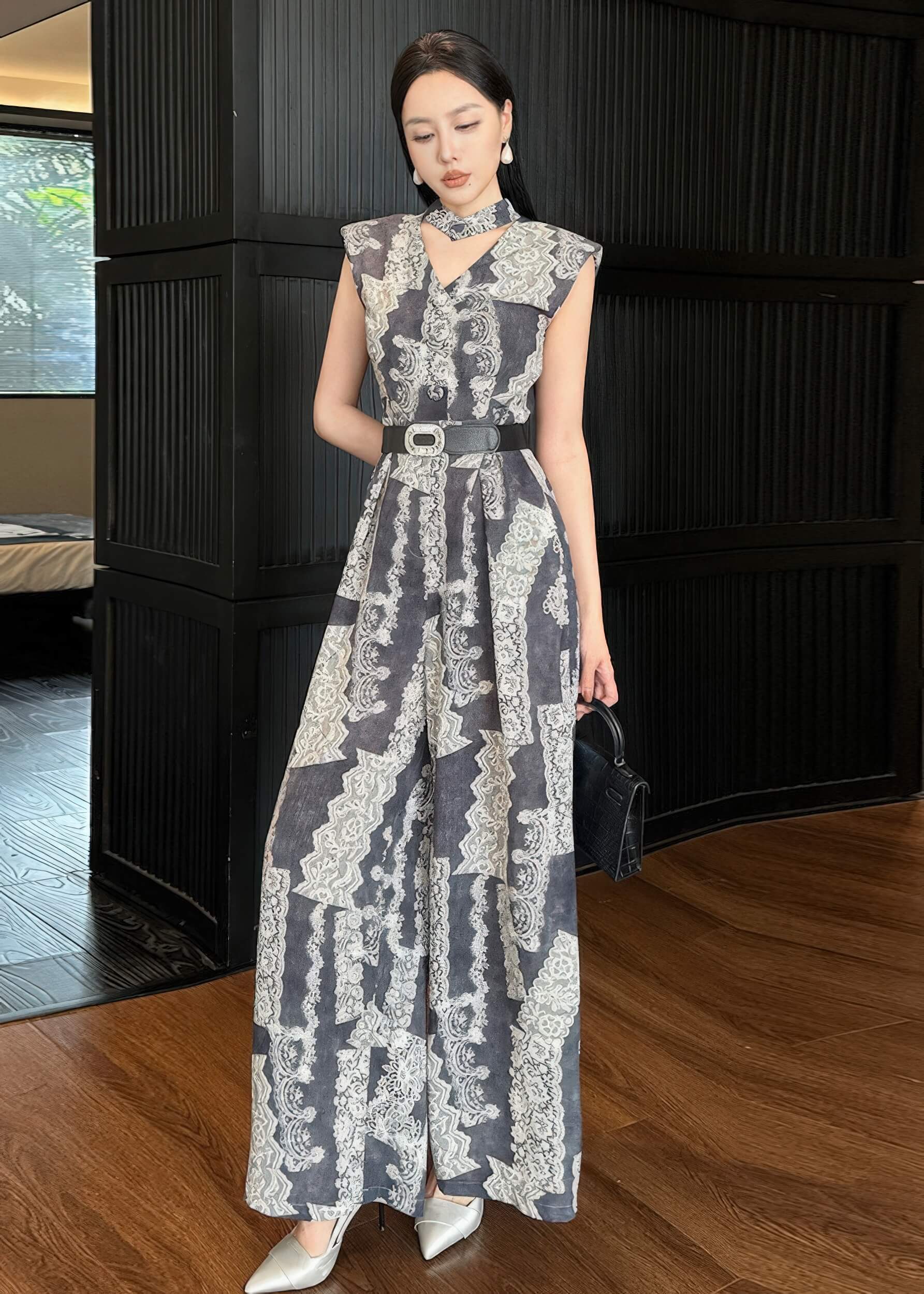 A slightly angled full-length pose where the woman looks toward the camera. This shot emphasizes the "halter-neck" effect created by the v-neckline paired with the separate neckband, as well as the flowy drape of the wide-leg trousers on a wooden floor.