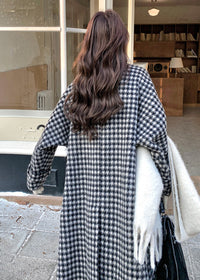 Rear view of a woman with long wavy brown hair wearing a long houndstooth patterned coat.