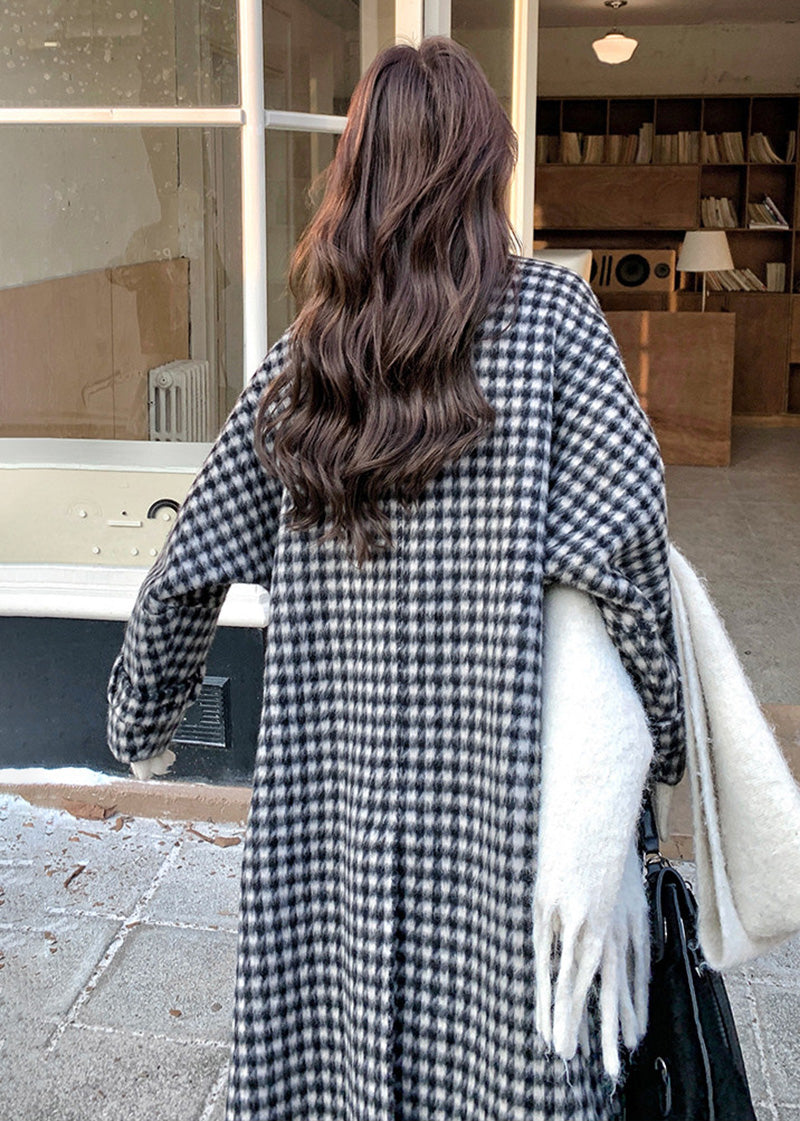 Rear view of a woman with long wavy brown hair wearing a long houndstooth patterned coat.