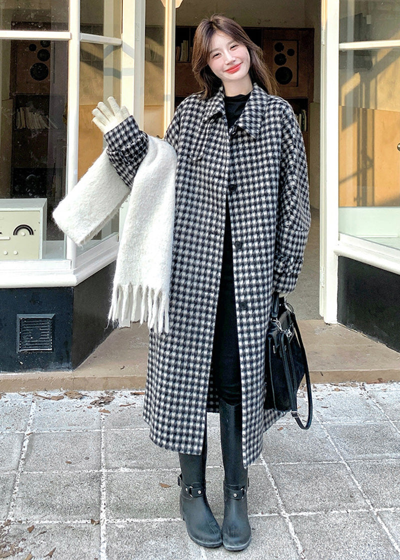 A woman waving while wearing an open houndstooth coat, white gloves, and carrying a thick white scarf.