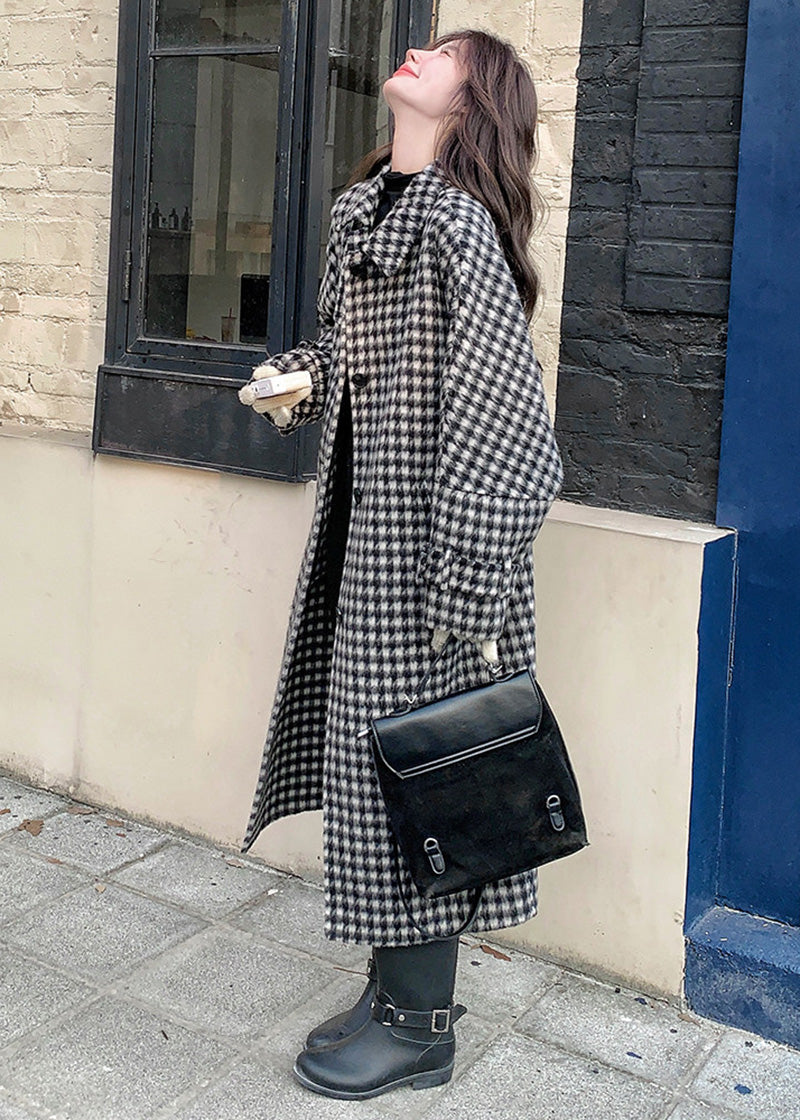 Side profile of a woman in a houndstooth coat looking upward while holding a small book and a black handbag.