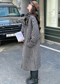 Profile view of a woman in a houndstooth coat and newsboy cap looking up toward a Land Rover.