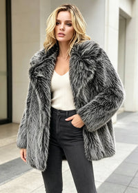 Full front view of a woman outdoors modeling an open charcoal grey textured faux fur coat over a white top and black pants.
