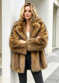 Front view of a blonde woman leaning against an outdoor pillar, wearing a brown faux fur coat over a white top and dark jeans with arms crossed.