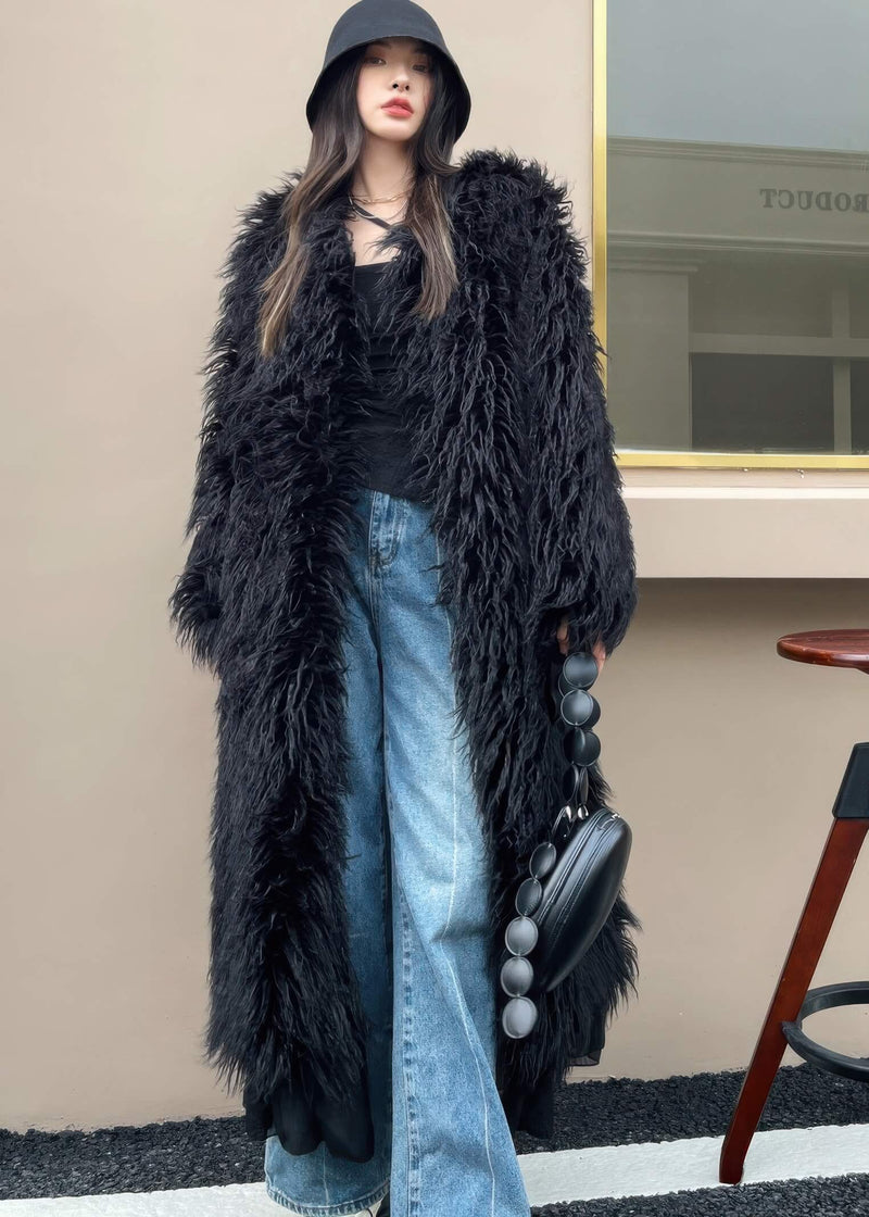 Full-length front view of a woman wearing a black shaggy faux fur long coat with wide-leg blue jeans and a black bucket hat.