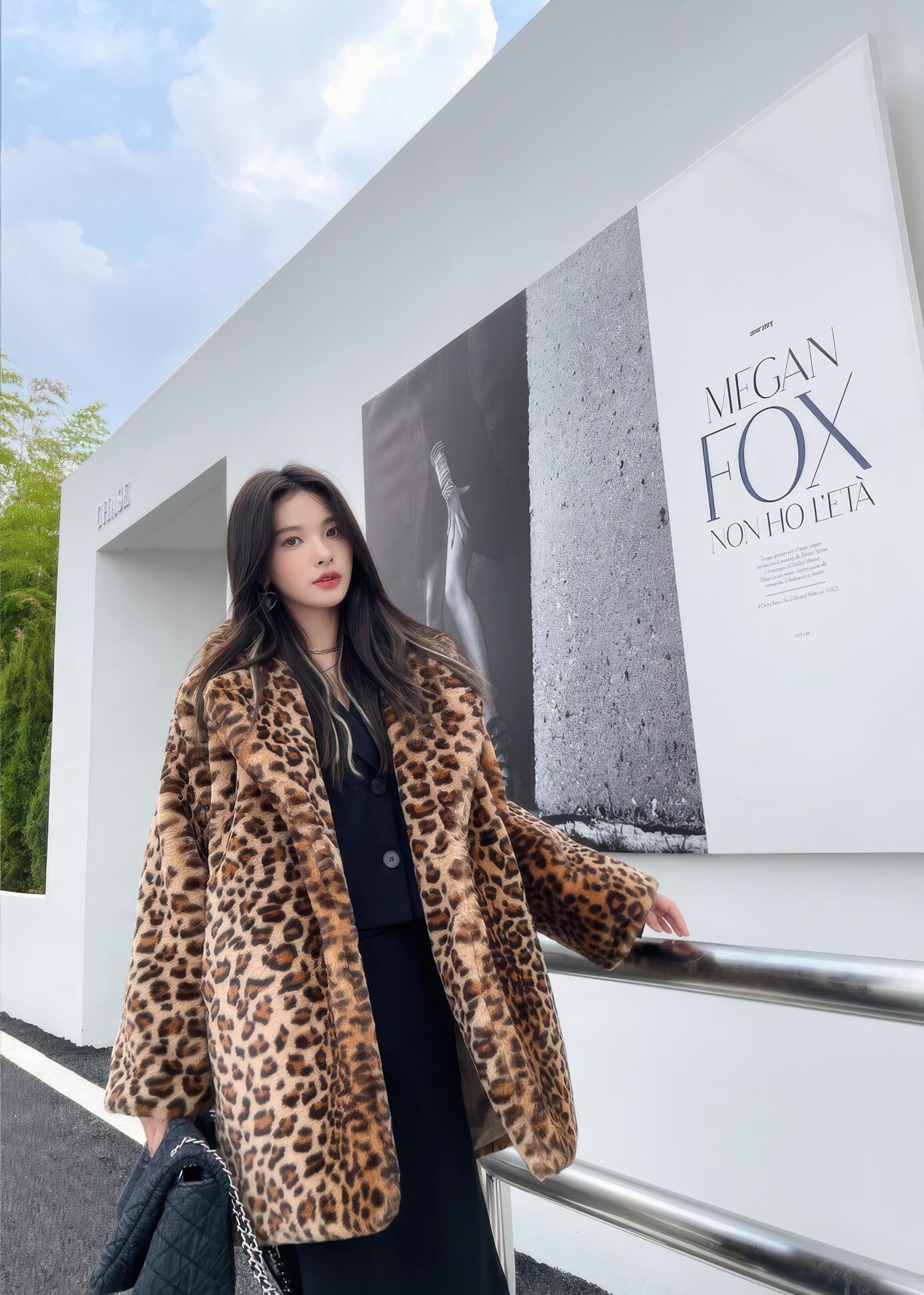 Full-length view of a woman wearing a leopard print fur coat over a black two-piece set, holding a quilted denim bag.