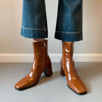 A front-facing view of the tan boots being worn with cropped denim, emphasizing the sleek silhouette of the square toe.