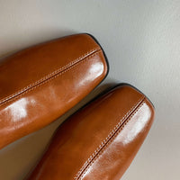 A close-up top view of the tan leather boots, focusing on the square toe design and the decorative vertical stitching running down the center.