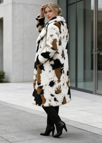 Model touching her hair while posing in a stylish cow print long faux fur jacket with wide lapel collar.