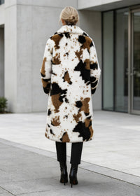 Full back view showing the length and pattern details of a women's abstract cow print long faux fur coat.