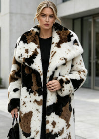 Medium close-up portrait of a blonde model looking at the camera in a plush cow spot pattern faux fur coat.