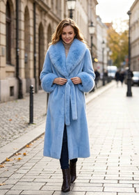 Full-body front look of a woman wearing a light blue belted faux fur maxi coat walking outdoors.