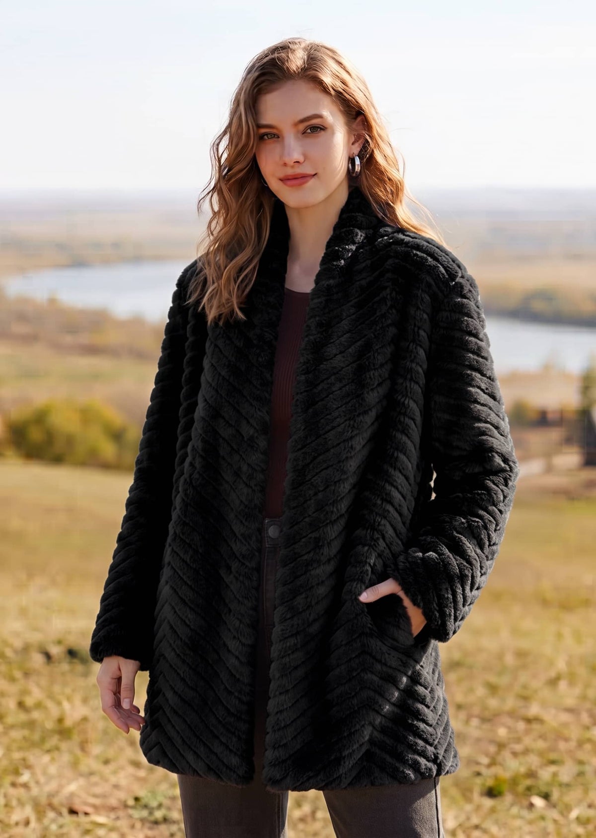 Front view of woman wearing black chevron shawl collar faux fur coat with side pockets