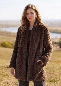 Full front view of woman wearing brown chevron faux fur winter coat in outdoor setting
