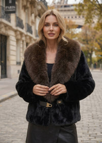 Close-up front view of woman wearing black faux fur jacket with dark brown contrast fur collar and front buckle detail