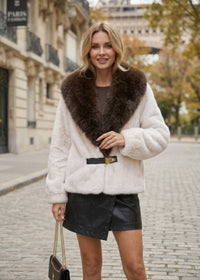 Front view of woman wearing cream white faux fur jacket with brown lapel collar and buckle closure