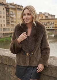 Alt Text: Close-up of woman wearing taupe brown faux fur jacket with dark plush collar and front buckle