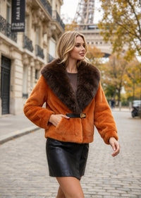 Woman walking outdoors wearing orange faux fur jacket with dark brown contrast fur collar