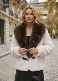 Close-up front view of woman wearing cream off-white faux fur jacket with dark brown collar