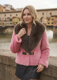 Woman wearing dusty pink faux fur jacket with dark brown contrast lapel collar and buckle detail
