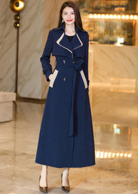 A medium shot of the Vivian Seven trench coat featuring unique cream-colored accents on the pocket welts and oversized lapels, styled with hands in pockets for a chic, modern look.