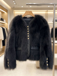 A black faux fur jacket with gold button accents hanging on a wooden hanger in a boutique setting.