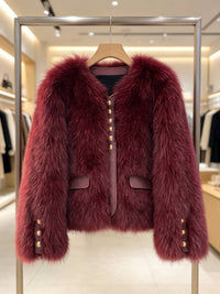 A burgundy faux fur jacket with gold-tone decorative buttons, displayed on a wooden hanger inside a metal clothing rack in a boutique setting.