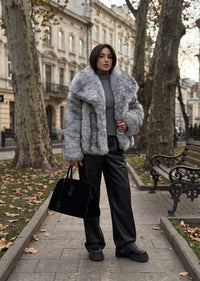Full-length street style look featuring a woman in an oversized collar gray faux fur jacket, gray turtleneck, and black straight-leg trousers