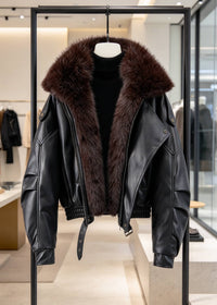 Black faux leather jacket featuring dark brown faux fur trim collar and belted waist displayed on black clothing rack.