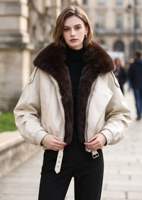 Front view of model wearing cream white faux leather jacket with dark brown faux fur lapels.   