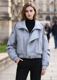 Front view of model wearing light blue faux leather jacket with faux fur collar removed, zipped up with belt tied.