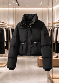 A black puffer jacket with a high stand-up collar and front zipper, displayed on a clothing rack inside a modern, well-lit clothing store.