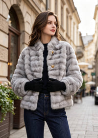 Front street style view of a woman wearing a light grey horizontal grooved stand collar faux fur cropped jacket with gold buttons