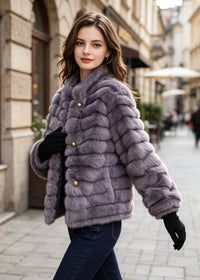 Side profile walking pose of a model wearing a purple grooved faux fur crop coat with gold snap buttons