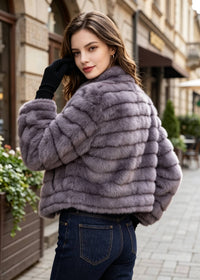 Back and shoulder view of a woman wearing a purple horizontal grooved cropped faux fur jacket paired with blue jeans