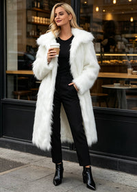 Blonde woman holding a coffee cup outside a cafe wearing a long white shaggy faux fur coat with oversized notch lapels over an all-black outfit.