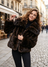 Playful street fashion shot of a woman smiling while wearing a fluffy espresso brown oversized lapel faux fur cropped jacket