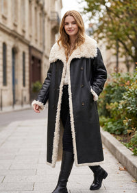 Full-length front shot of a woman wearing an open black faux shearling leather longline winter coat.