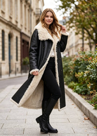 Fashion model walking in a long black faux shearling lined leather coat showing the soft fleece inner layer.