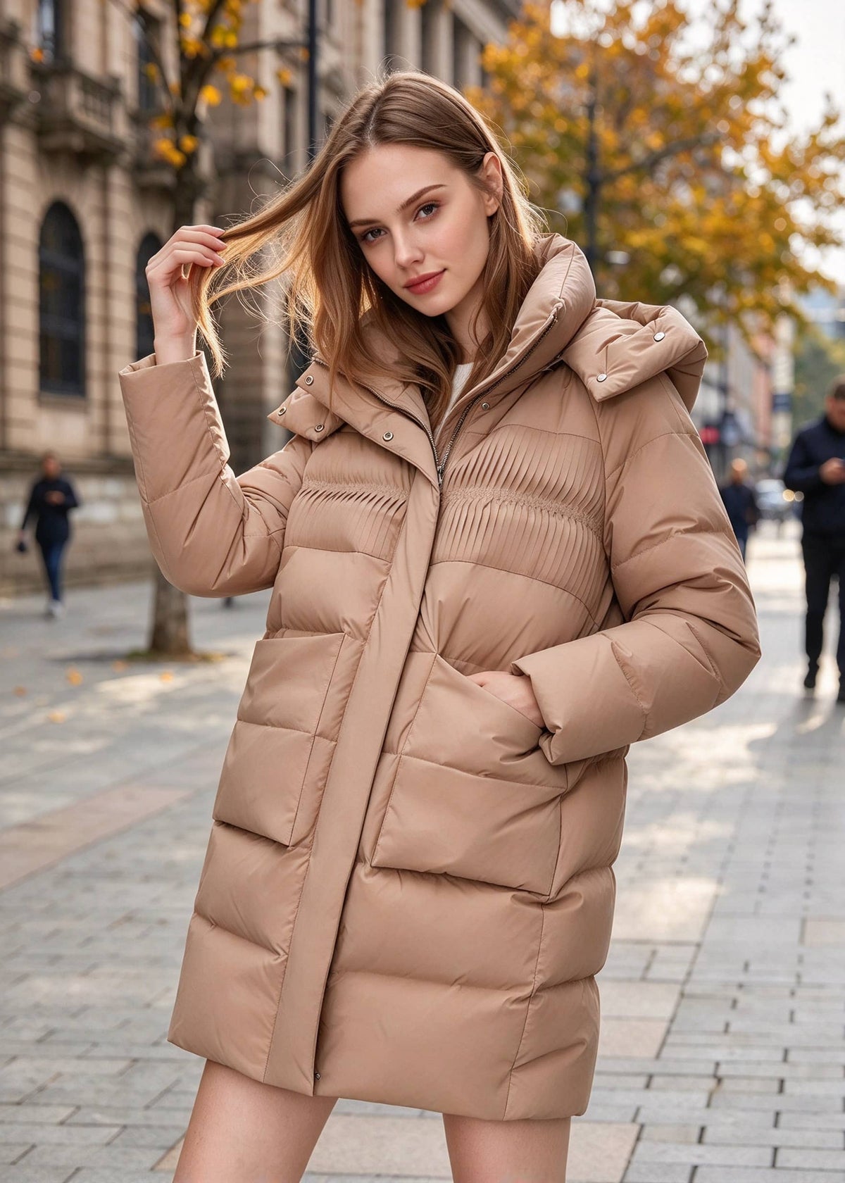 Playful outdoor pose of woman wearing a khaki tan mid-length down parka coat with hood, adjusting hair on autumn city street.
