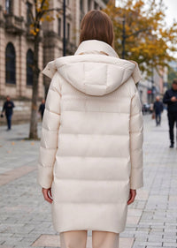 Full back view of woman wearing an off-white long hooded quilted down puffer coat with attached hood and horizontal baffles.